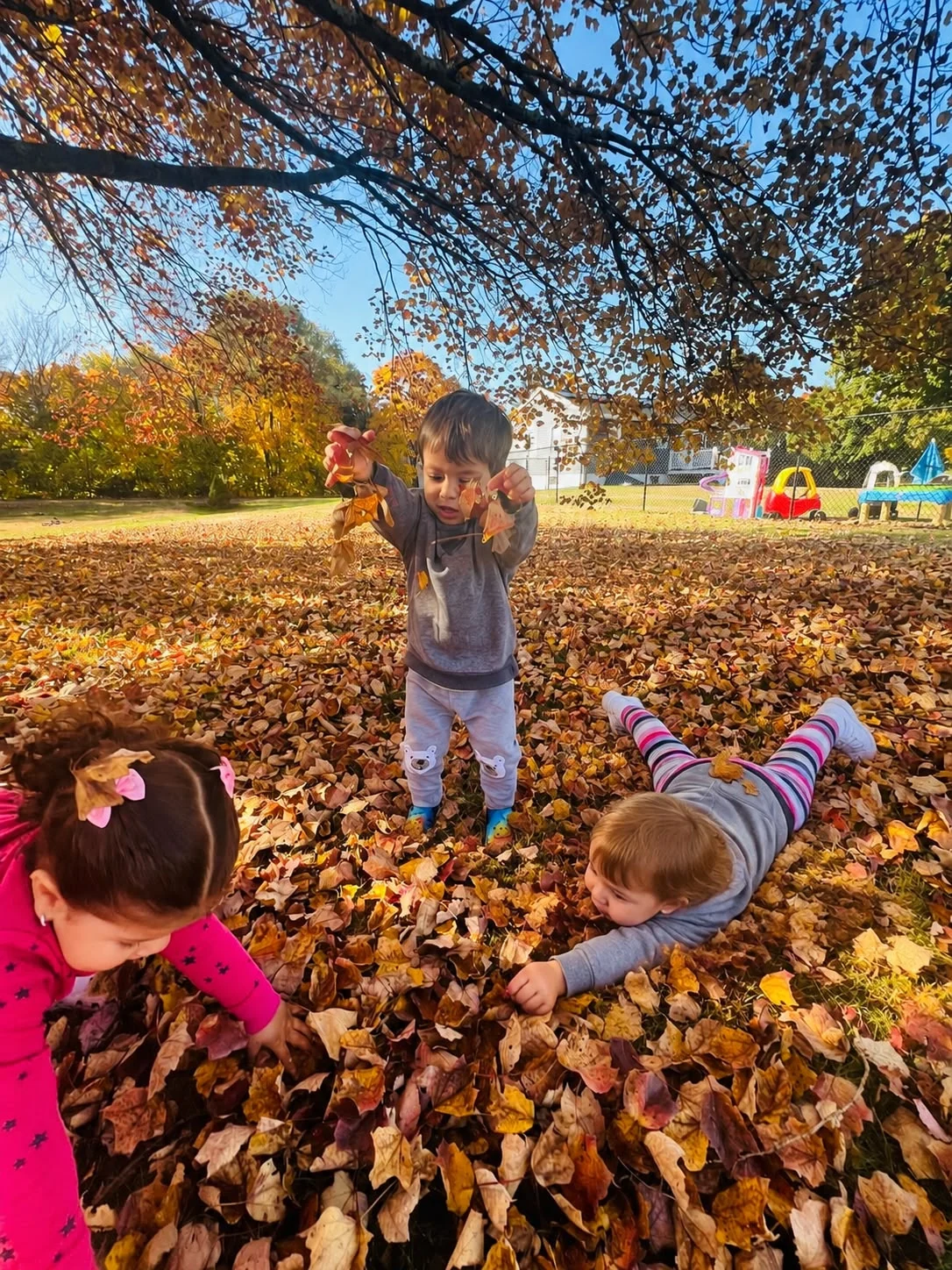 Children playing outside in fall leaves at Care's Corner Childcare